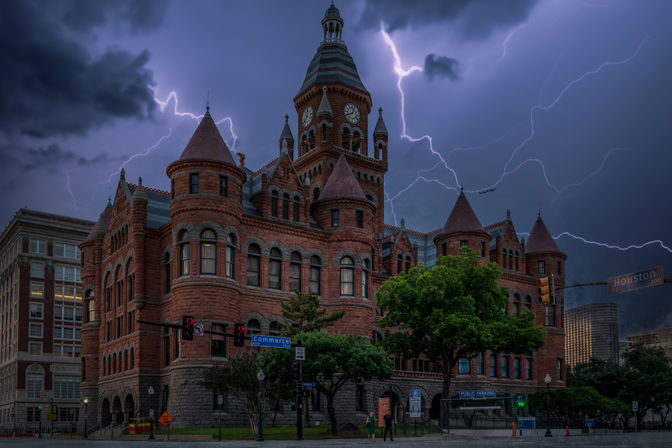 Historic red-brick Romanesque courthouse at Commerce and Houston streets in downtown, dramatic stormy sky with multiple lightning bolts illuminating the clock tower