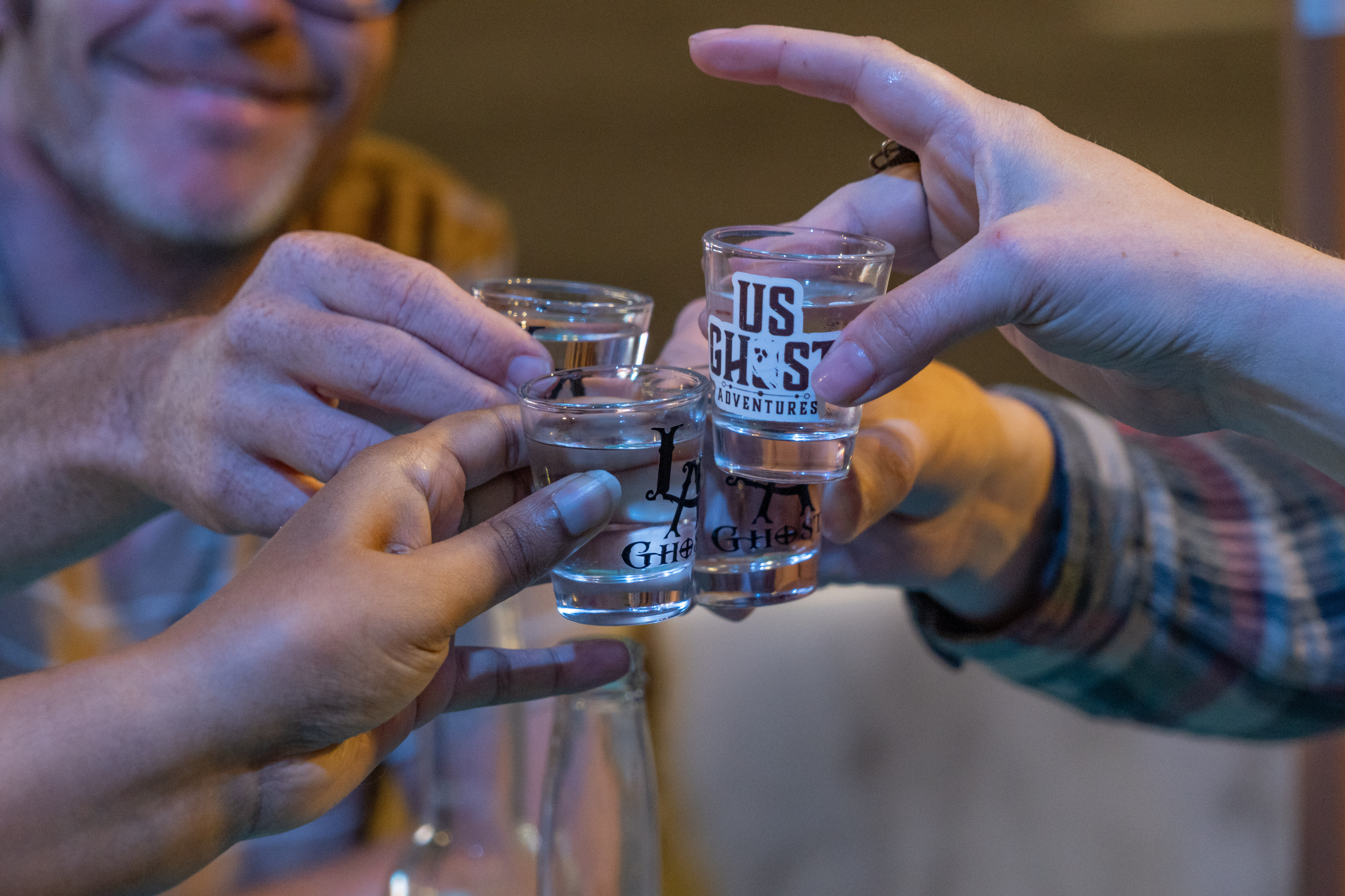 Group of friends clinking shot glasses in a cozy bar for a night out toast