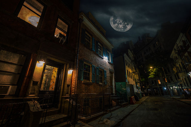 Moonlit urban street with a historic brick brownstone, glowing front doorway, blue shutters, wrought-iron railings and dim streetlights