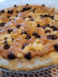 Close-up of a homemade chocolate chip cookie pie with golden, gooey filling studded with dark and white chocolate chips and a flaky pie crust on a lace tablecloth