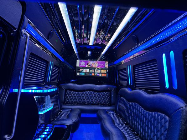 Luxury party limo interior with blue LED lighting, quilted leather bench seats, mirrored ceiling, built-in bar and flat-screen TV — sleek nightlife transport.