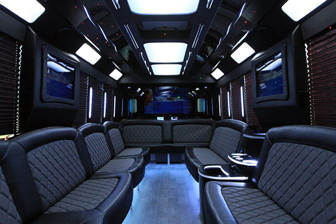 Luxury party bus interior with quilted leather wraparound seating, LED ambient ceiling lights, built-in TVs and wood-look floor