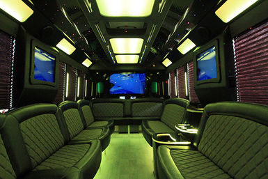 Luxury party bus interior — quilted black leather wraparound seating, green LED floor and starlit ceiling, multiple flat-screen TVs and cupholders, spacious mobile lounge for group events.