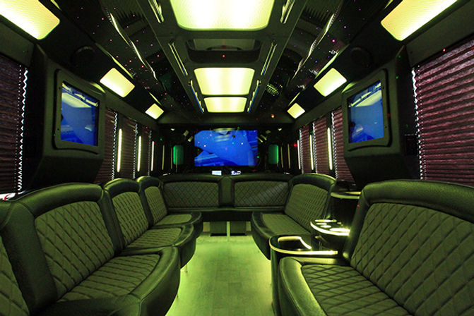 Luxury party bus interior — quilted black leather wraparound seating, green LED floor and starlit ceiling, multiple flat-screen TVs and cupholders, spacious mobile lounge for group events.
