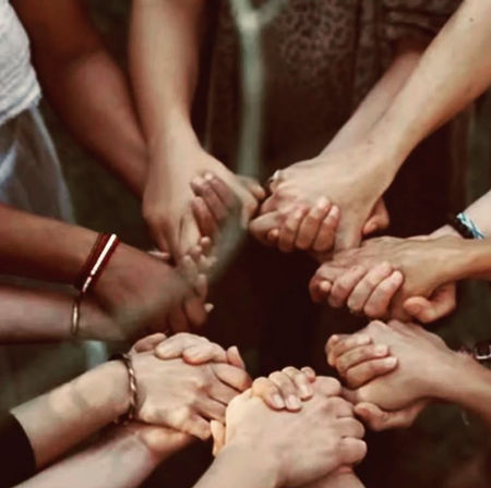 Circle of hands clasped together in a close-knit group, symbolizing unity, support, community, and teamwork.