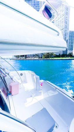 White yacht deck overlooking turquoise downtown waterfront marina with palm trees and glass high-rise skyline