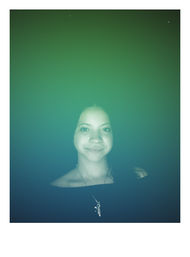 Close-up portrait of a smiling young woman framed low in the image with a green-to-blue gradient overlay, wearing an off-shoulder top and spiral pendant necklace — moody, studio-style headshot.