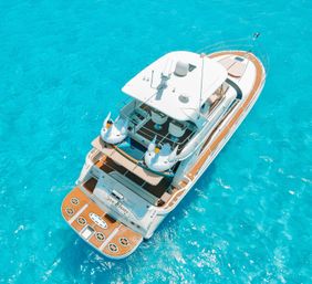 Aerial view of a luxury white yacht with teak decks and swan-shaped inflatable floats drifting on crystal-clear turquoise tropical water