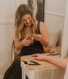 Smiling jewelry maker adjusts a delicate bracelet with pliers on a client's hand at a cozy craft table