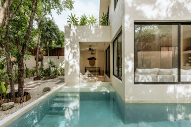 Sun-dappled modern tropical villa with private plunge pool, shaded patio swing and lush garden landscaping.