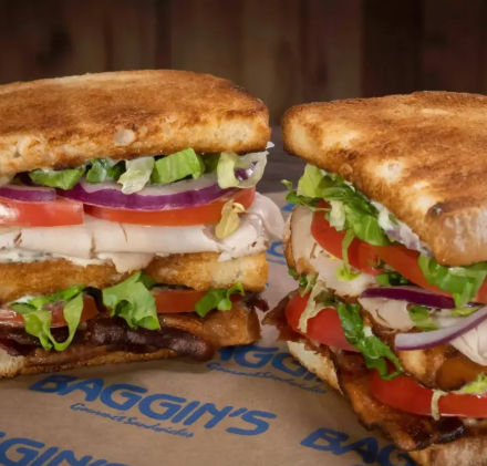 Close-up of two toasted deli-style club sandwiches stacked with sliced turkey, crispy bacon, tomato, red onion, shredded lettuce and mayonnaise on golden toasted bread