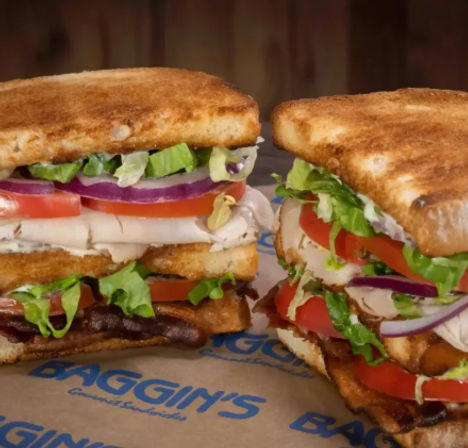 Close-up of two toasted deli-style club sandwiches stacked with sliced turkey, crispy bacon, tomato, red onion, shredded lettuce and mayonnaise on golden toasted bread