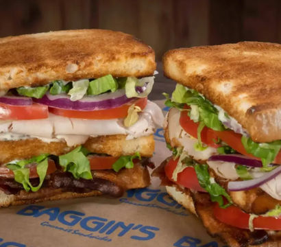 Close-up of two toasted deli-style club sandwiches stacked with sliced turkey, crispy bacon, tomato, red onion, shredded lettuce and mayonnaise on golden toasted bread
