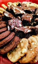 Assorted chocolate swirl brownies with stacked chocolate cookies and white chocolate chip cookies on a red serving tray, bakery dessert platter