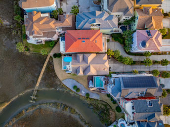 Aerial view of colorful waterfront homes with private docks, backyard pools and a winding coastal marsh canal