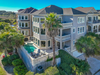 Sunny coastal three-story vacation home with wraparound balconies, palm trees and a private pool overlooking a marsh