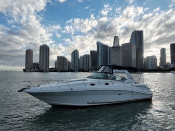 White cabin yacht on calm Biscayne Bay waters with Miami, Florida high-rise skyline and dramatic cloudy sky