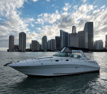 White cabin yacht on calm Biscayne Bay waters with Miami, Florida high-rise skyline and dramatic cloudy sky