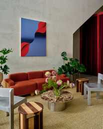 Stylish modern living room with a rust-orange sofa, blue and red abstract wall art, marble coffee table, tropical houseplants and woven jute rug — contemporary lounge interior
