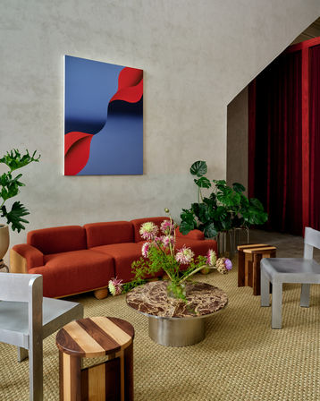 Stylish modern living room with a rust-orange sofa, blue and red abstract wall art, marble coffee table, tropical houseplants and woven jute rug — contemporary lounge interior