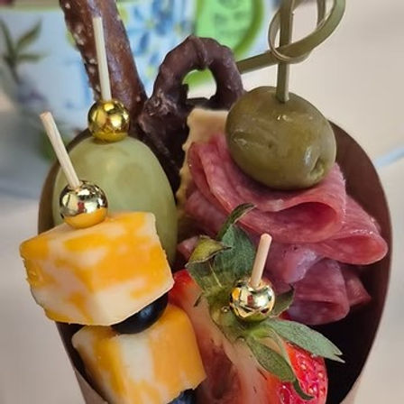 Mini charcuterie cone appetizer with skewered marbled cheddar cubes and black olive, folded salami, green olive, fresh strawberry and a chocolate-covered pretzel in a chocolate cup