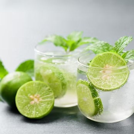 Zesty sparkling lime drink with fresh mint, ice and lime slices in clear glasses