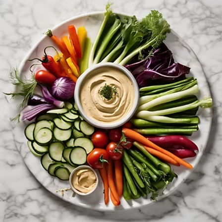 Colorful vegetable crudité platter with sliced cucumber, cherry tomatoes, carrots, bell peppers, radicchio, scallions and snap peas arranged around bowls of creamy hummus on a marble serving board