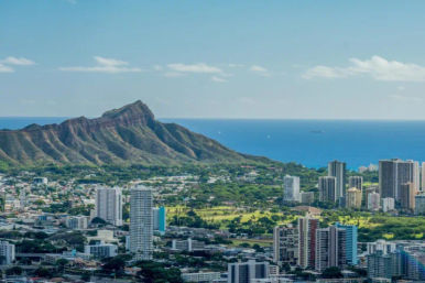 Aerial view of Honolulu skyline with Diamond Head volcanic crater and the blue Pacific Ocean under a sunny sky