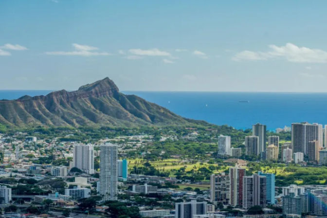 Sunny aerial view of Waikiki skyline in Honolulu, Oahu with Diamond Head crater and the blue Pacific Ocean