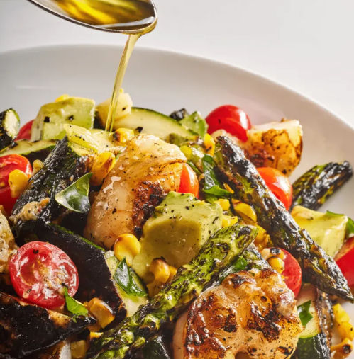 Grilled chicken salad with charred asparagus, avocado chunks, cherry tomatoes, roasted corn and zucchini, fresh herbs and olive oil drizzle