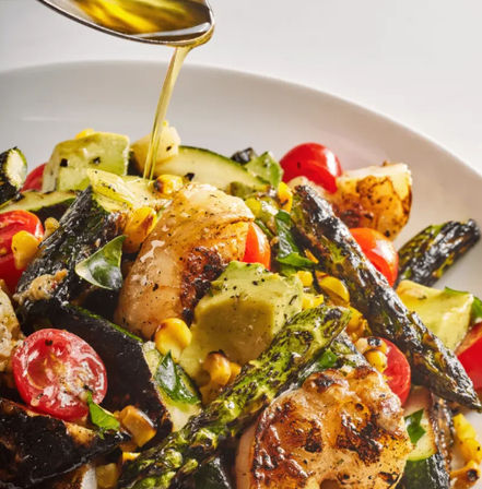 Grilled chicken salad with charred asparagus, avocado chunks, cherry tomatoes, roasted corn and zucchini, fresh herbs and olive oil drizzle