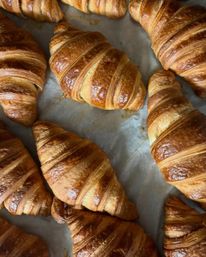 Close-up of freshly baked golden, flaky croissants on parchment paper, artisan French-style breakfast pastries.