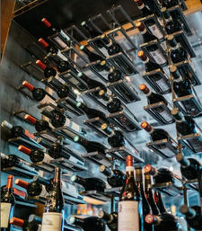 Modern metal wall wine rack holding rows of horizontal wine bottles in a stylish restaurant wine bar display