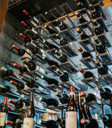 Modern metal wall wine rack holding rows of horizontal wine bottles in a stylish restaurant wine bar display