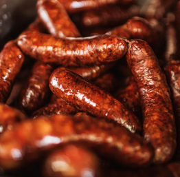 Glistening smoked sausage links, richly browned and seasoned and piled together for a savory barbecue.