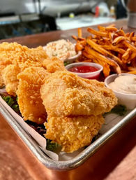 Pub-style crispy golden fried fish fillets with sweet potato fries, coleslaw and dipping sauces (ketchup and tartar) served on a metal tray