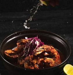 Charred spiced shrimp with shredded purple cabbage in a black bowl, zesty lime juice drizzling from above and a lime wedge at the rim