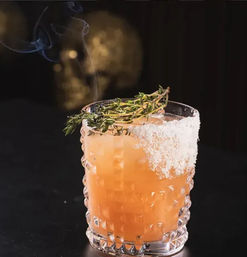 Smoked peach-orange craft cocktail in a textured rocks glass with a salt rim and charred thyme garnish, wisps of smoke rising