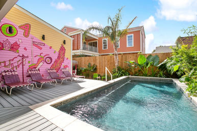 Sunny backyard plunge pool with turquoise water, pink Louisiana mural, palm tree and lounge chairs