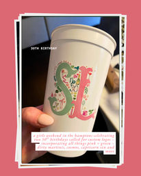 Festive white party cup held by a hand with pale pink nails, featuring a pastel green and pink 'SL' monogram filled with tiny icons (martini glass, champagne bottle, gift, hearts) and overlaid text '30th Birthday' — playful Hamptons girls‑weekend birthday vibe.