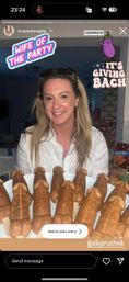 Smiling woman in a white blouse holding a plate of penis-shaped waffle pops on sticks in a kitchen, Instagram story stickers reading “Wife of the Party” and “It’s Giving Bach” with an eggplant graphic — playful bachelorette party dessert shot.