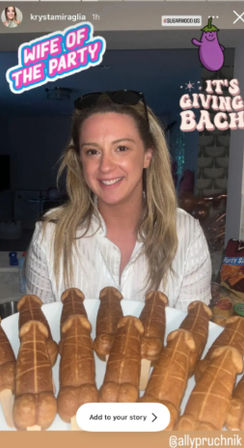 Smiling woman at an indoor bachelorette party holding a platter of novelty adult-shaped pastries, with playful stickers saying “Wife of the Party” and “It’s Giving Bach” visible