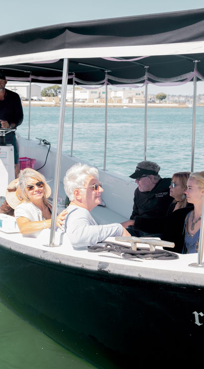 Small covered sightseeing boat with a group of adults and a captain enjoying a relaxing harbor cruise on turquoise coastal waters under a sunny sky