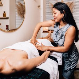 Spa therapist giving a relaxing abdominal massage to a client on a towel-covered table in a cozy wellness treatment room