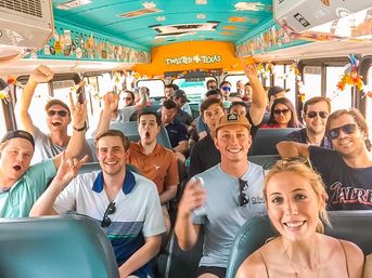 Smiling group of young adults cheering inside a colorful, decorated Texas party bus