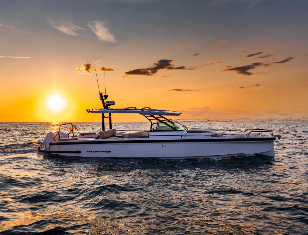 Sleek motorboat gliding across choppy ocean waves at golden sunset with vibrant orange sky and sun reflecting on the water