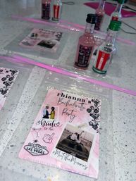 Pink-themed bachelorette party favor on a speckled countertop: a custom itinerary card with photos and 'bride to be' graphics, pink plastic straws and several mini liquor bottles nearby — Cabo San Lucas party vibe.