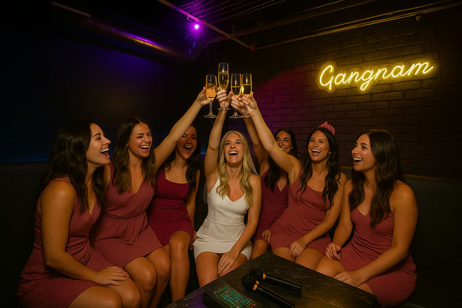 Group of women on a girls' night raising champagne flutes in a dim karaoke lounge with a neon sign, laughing and toasting.