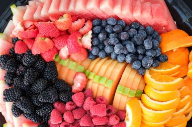 Vibrant fresh fruit platter with sliced watermelon, cantaloupe, orange wedges and piles of blueberries, strawberries, blackberries and raspberries