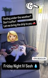 Person seated in a living room recliner with a small white dog on their lap, receiving a yellow IV drip hanging from a stand by the window, with text overlays promoting an at‑home IV therapy 'Friday Night IV Sesh'.